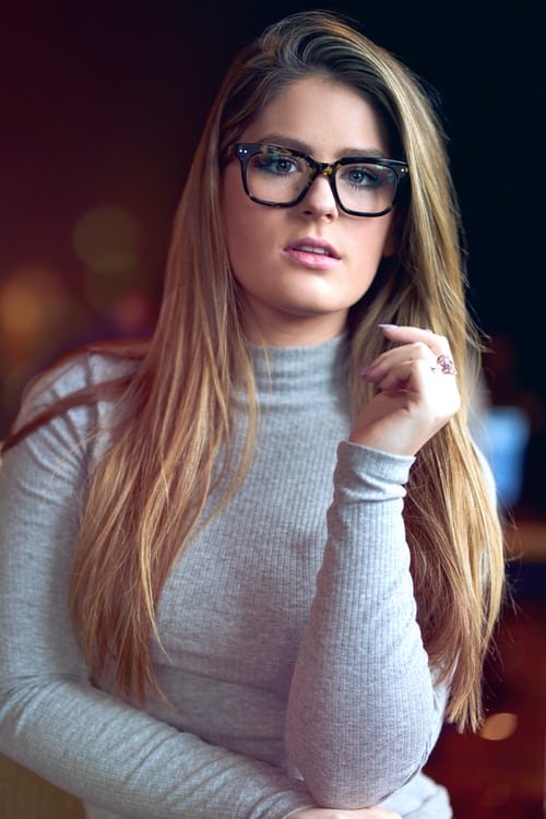 An intelligent woman in a grey sweater poses for her picture taken.
