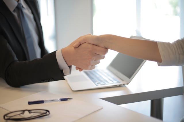 Debt relief expert shakes client hand in a bright office.