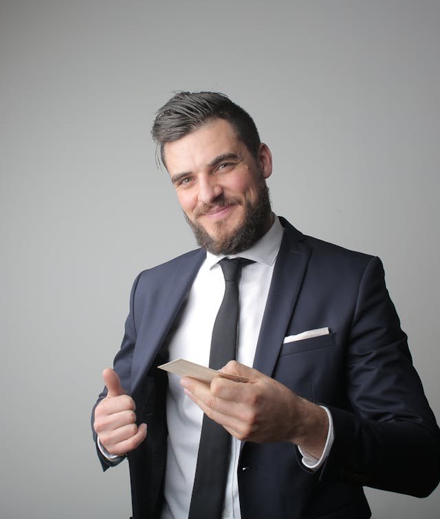 Man in black suit holding a business card | GTDR