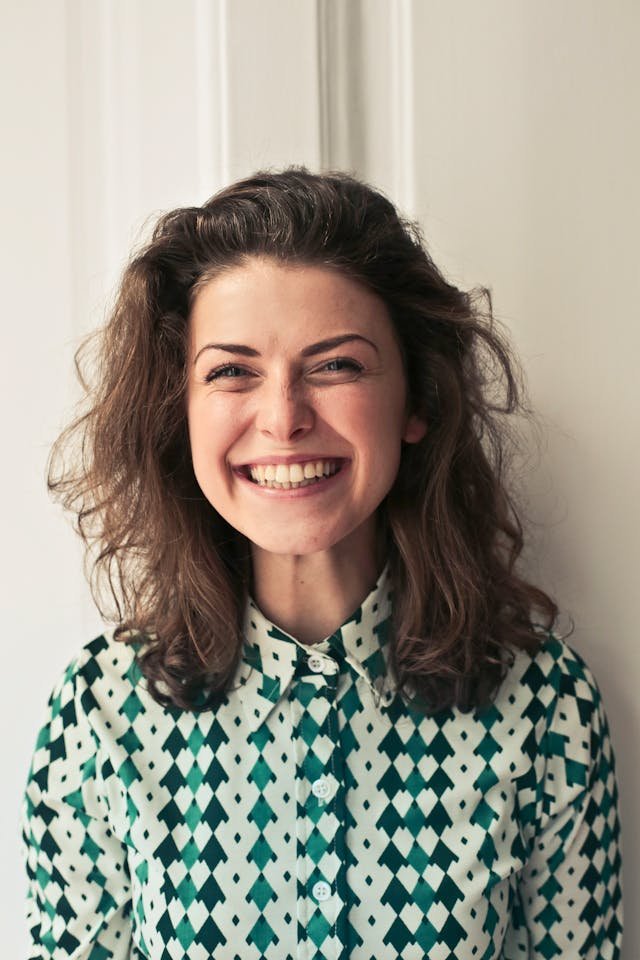 Woman In a green collared shirt, smiling for her photo taken.