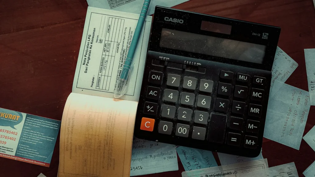 A calculator, cheque book and ledger on a desk, working out CRA debt for a consumer proposal